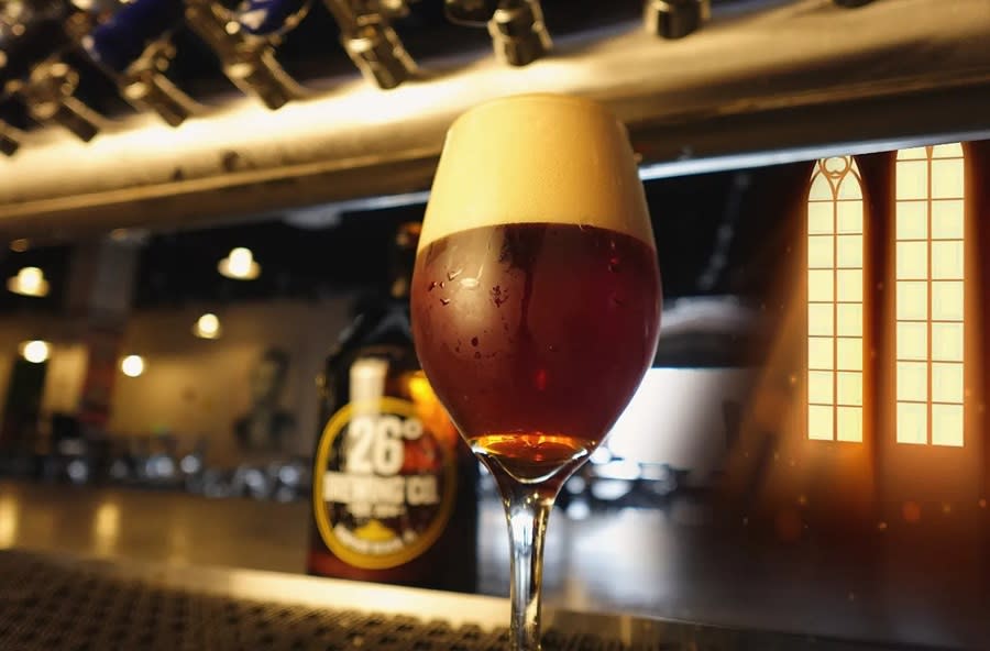 A glass of stout beer sitting on a bar with blurred out taps behind it.