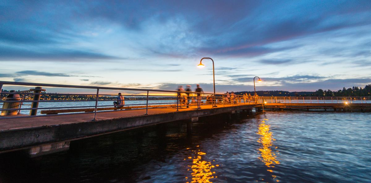 Gene Coulon Memorial Beach Park boardwalk along Lake Washington at sunset, featuring illuminated waterfront pathways, calm water reflections, and scenic shoreline views.