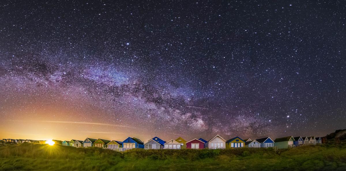 Multicoloured painted Mudeford Beach huts with the Milky Way