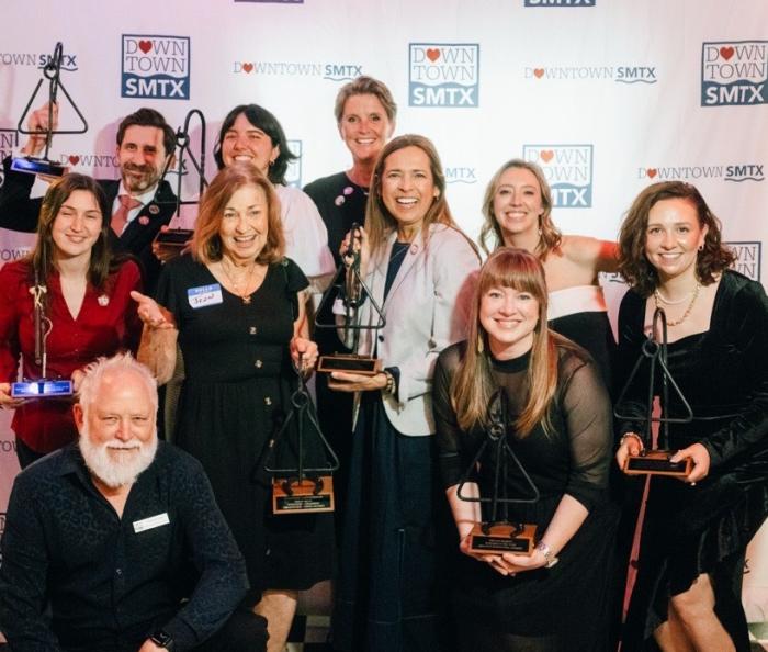 Group photo of award winners at the Love Downtown Awards holding their trophies, posed front of the Downtown SMTX step and repeat