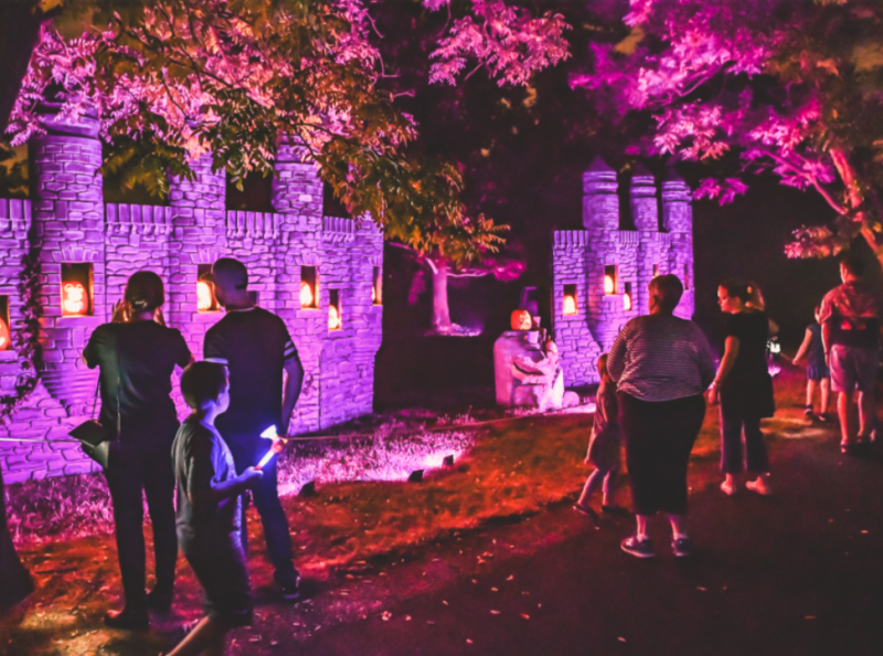 Families at Lincoln Hill Farms at night, looking at jack-o'-lanterns on a castle wall