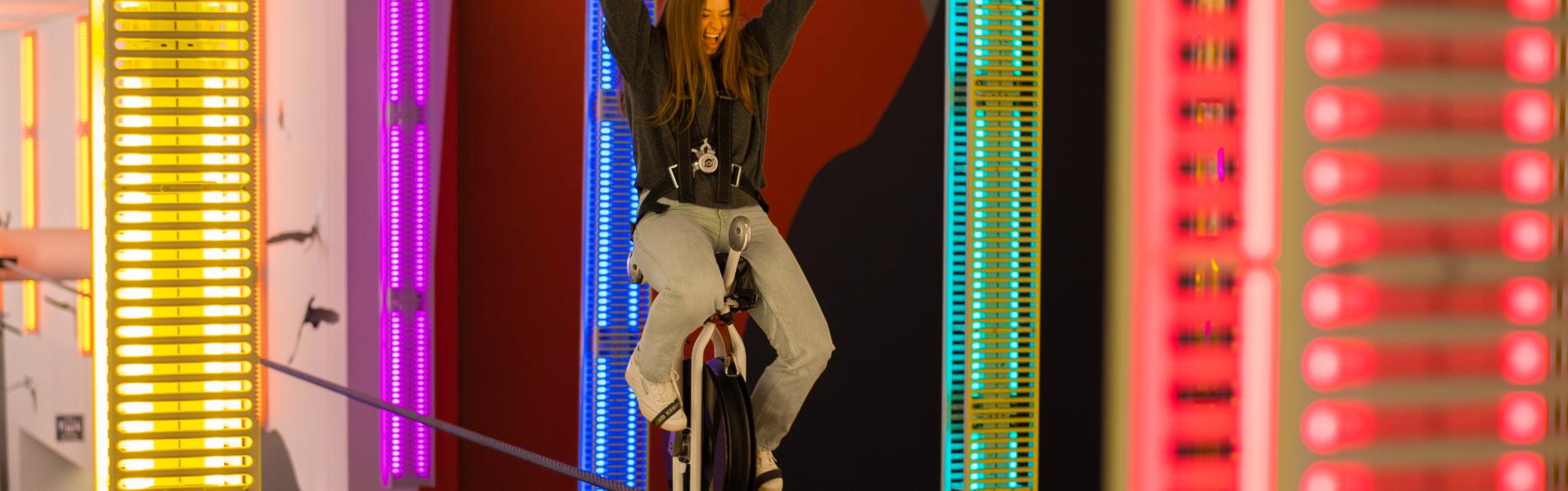Woman riding high-wire unicycle at COSI