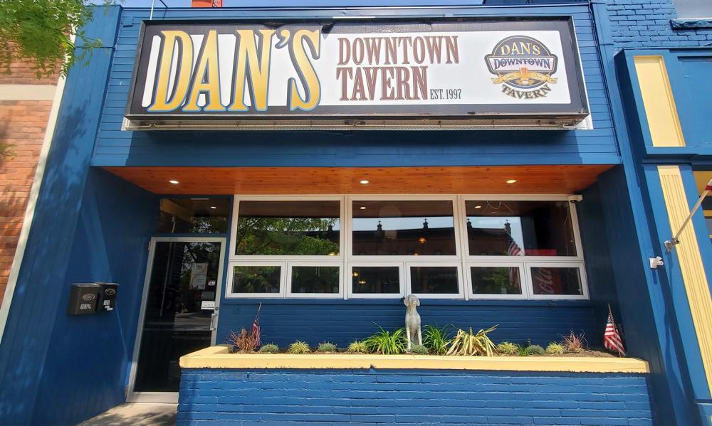 exterior photo facing front of building. Sign reads "Dan's Downtown Tavern". painted blue brick building, yellow lining.