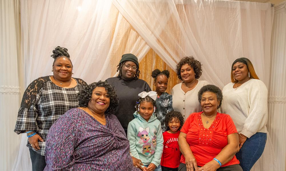 A family poses in front of a cream background