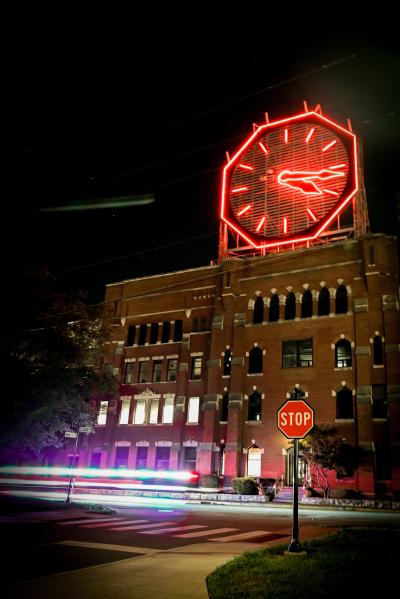 Colgate Clock glowing red with traffic headlights bluring