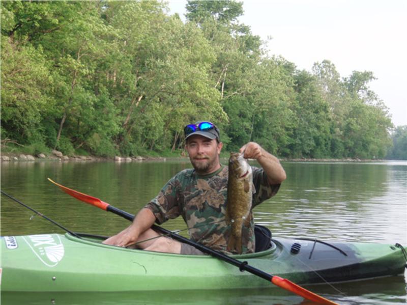 Man holding fish on a kayak