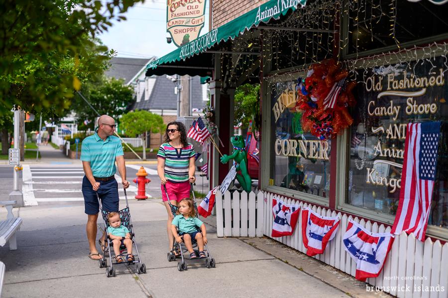 couple pushing two strollers down a downtown sidewalk