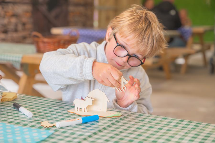 A young boy builds an Easter farm scene from plywood shapes at Cotswold Farm Park