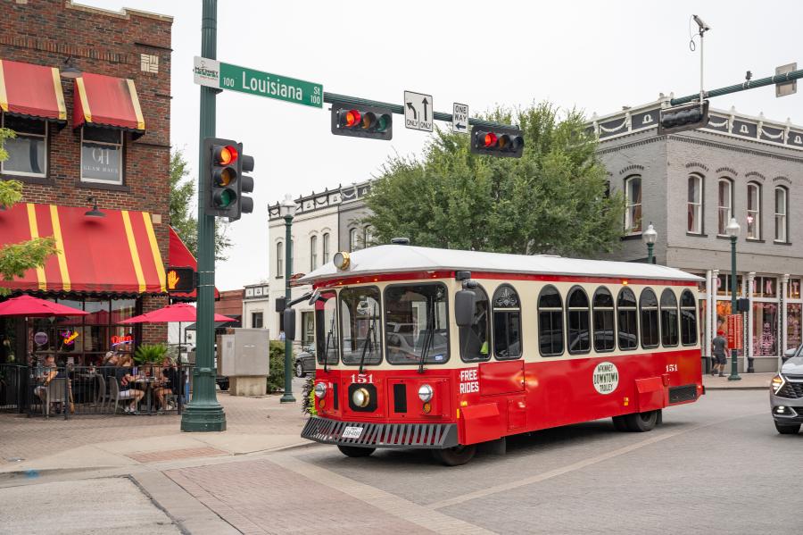 Red and white trolley driving down a historic street in Downtown McKinney