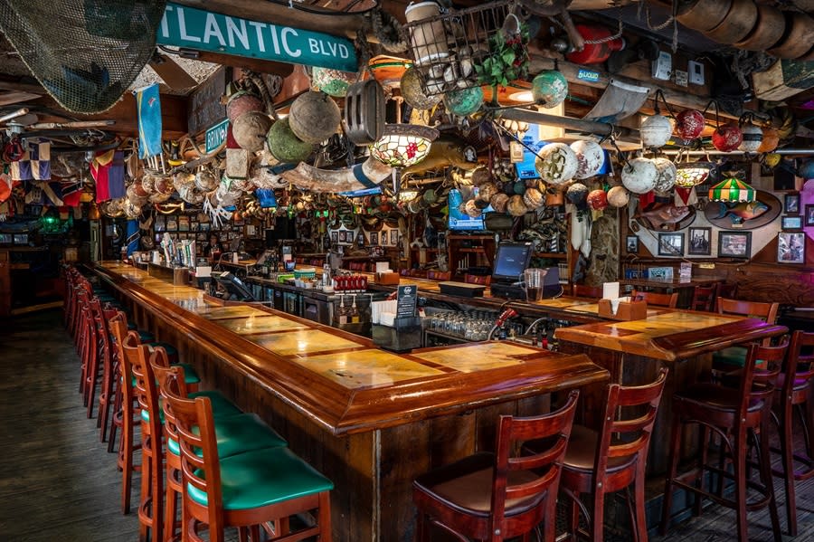 A classic wooden bar with lots of sea paraphernalia hanging from the ceiling along with televisions and hanging tiffany lights