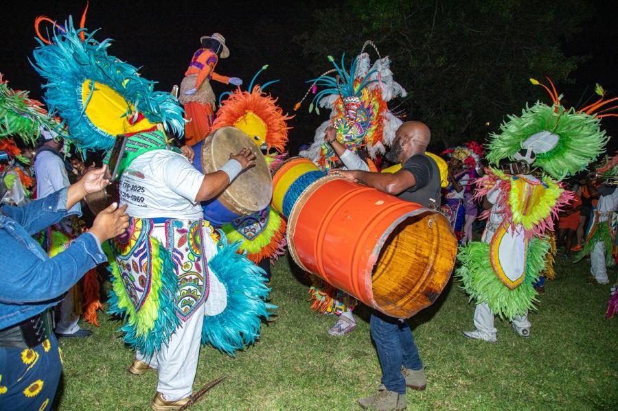 Men dressed in colorful native Caribbean costumes dancing and drumming.