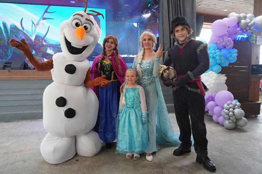 Adult actors dressed as characters from the animated movie Frozen, posing with a little girl dressed as Elsa at Galuppi's in Pompano Beach.