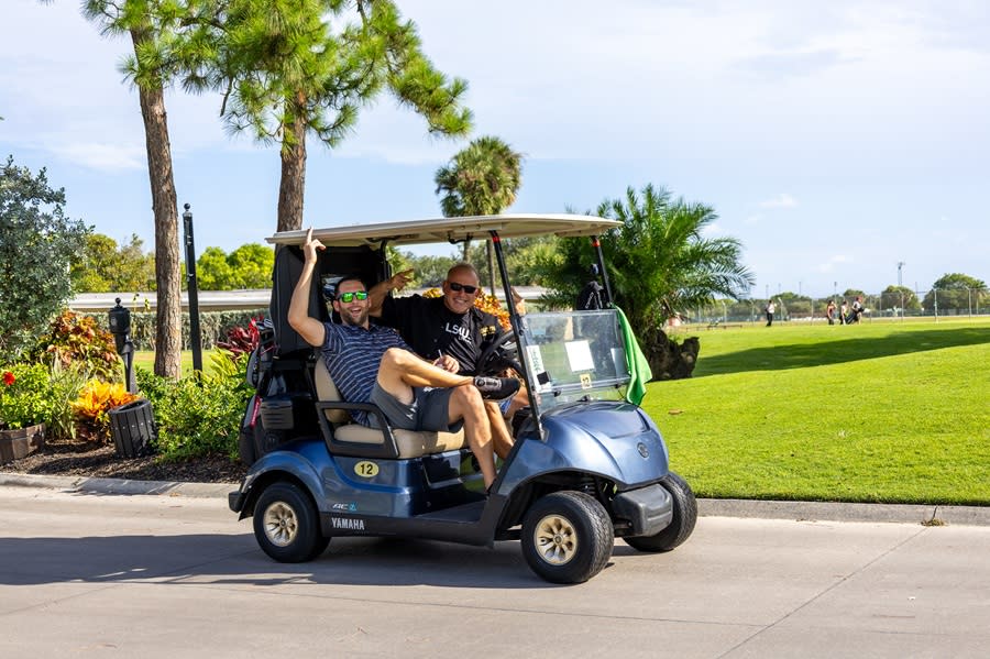 Two men riding a golf cart at the Pompano Beach Golf Club.