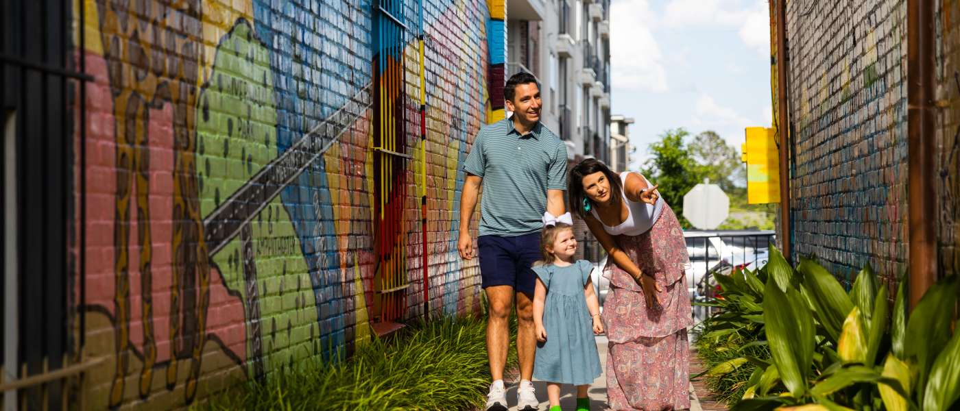 Family of three looks at a brightly colored mural