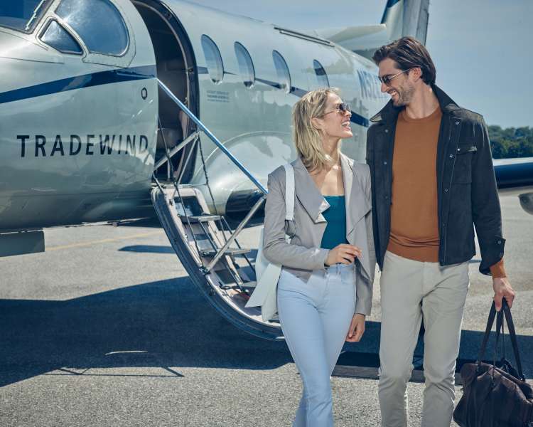 A couple standing next to a Tradewind plane.
