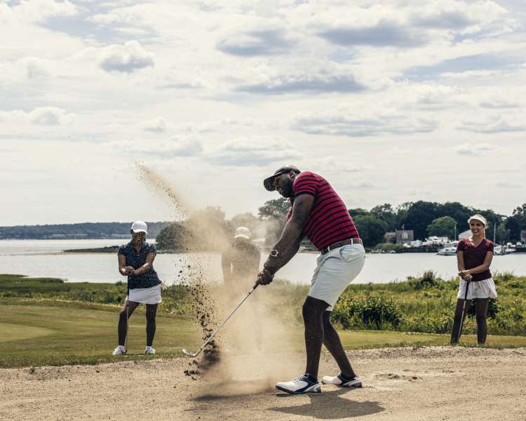 Man Hitting A Ball In A Sand Trap At Harbor Lights Golf In Rhode Island
