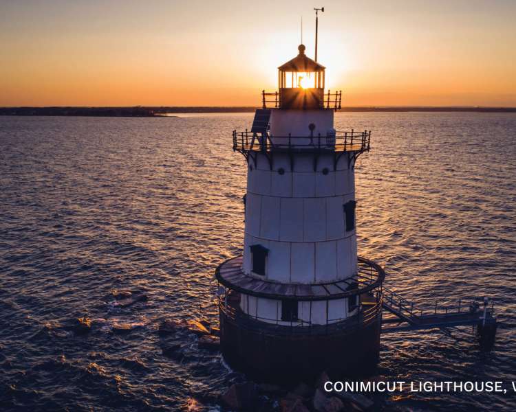The Conimicut Lighthouse, surrounded by water, at sunset.