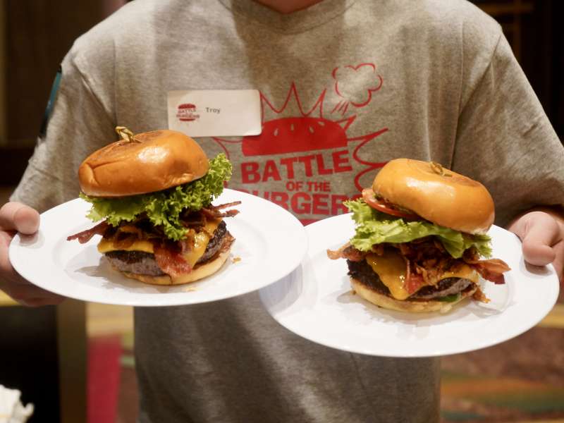 A person holding two burgers on plates