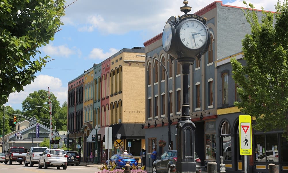 colorful buildings line a street. A clocktower stands at the front of the street.
