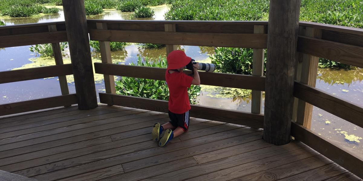 A child looks through a telephoto lens at Cattail Marsh in Beaumont, TX