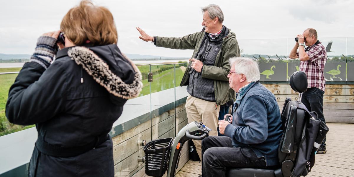 A wheelchair user birdwatching with family on the accessible estuary tower at WWT Slimbridge near Bristol - credit WWT Slimbridge Wetland Centre