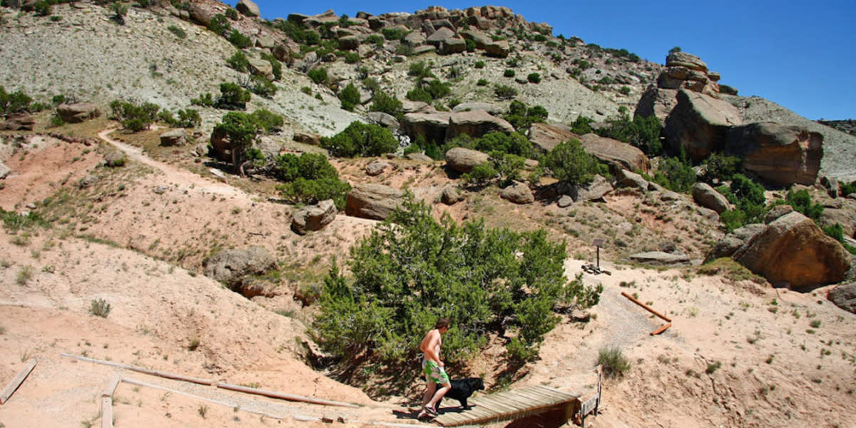 A man and dog descend a trail at Cottonwood Creek Dinosaur Trails near Casper, WY