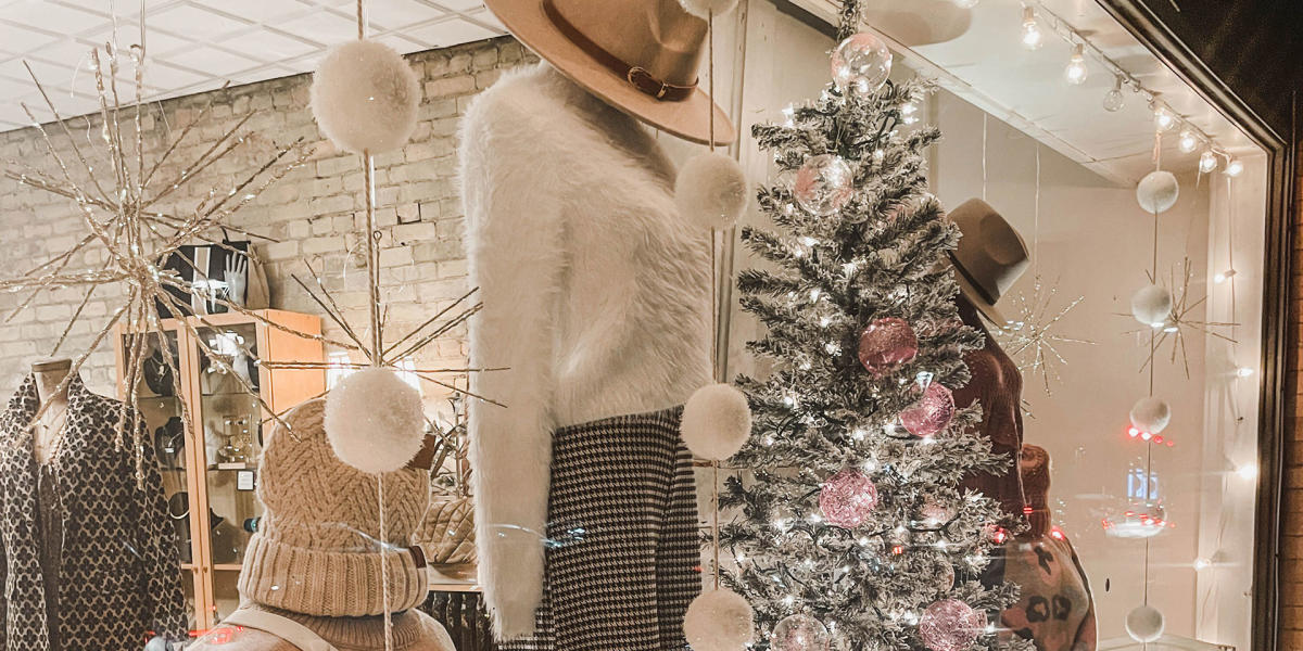 a clothing storefront with holiday decorations and a christmas tree with lights.