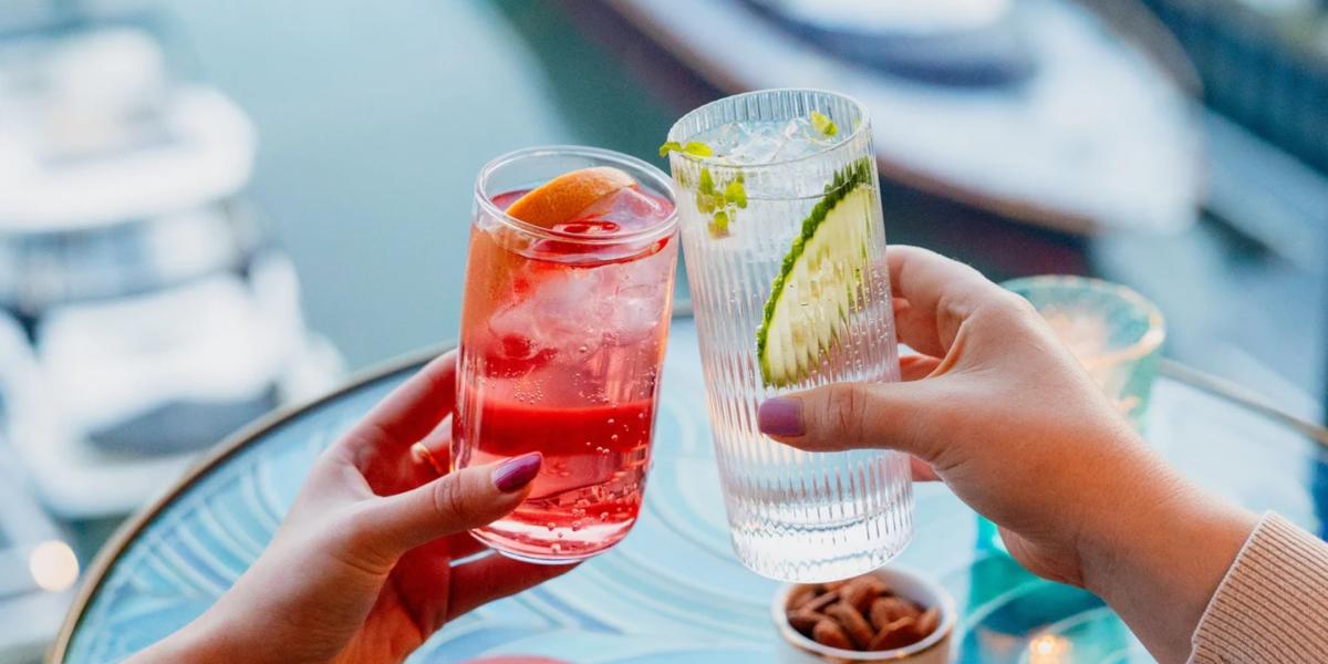 People clinking cocktails together at HarBAR on 6th rooftop bar