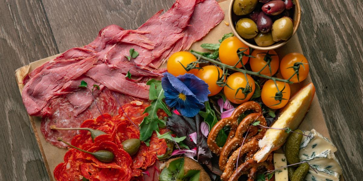 Colourful charcuterie board from Porters filled with choice meats, fresh fine tomatoes, pretzels, olives, cheeses and edible flowers