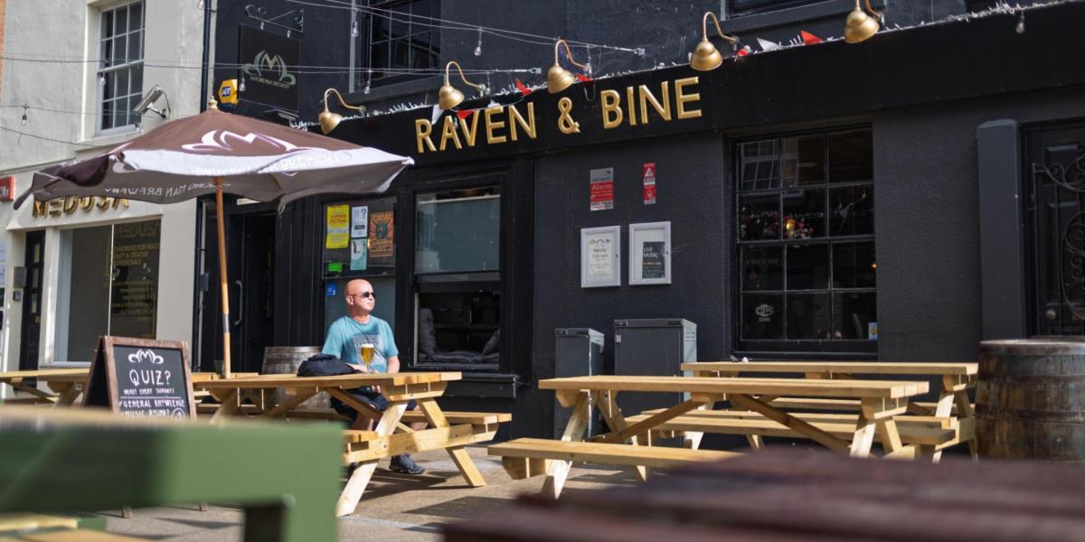 Raven & Bine exterior with man sitting at a picnic bench out on the front terrace