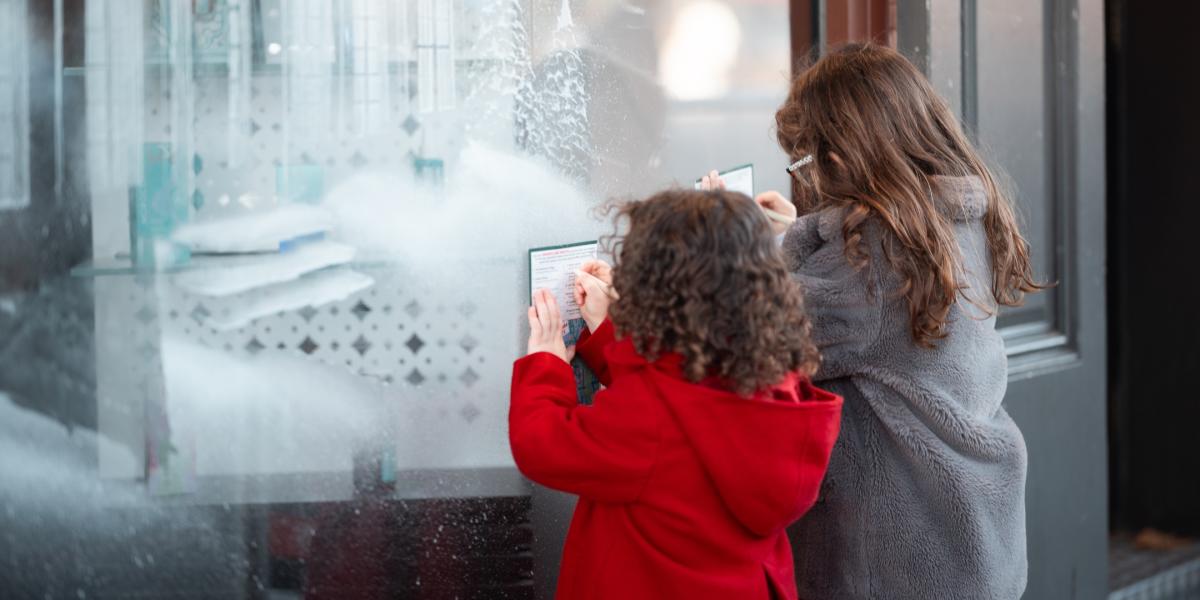 Two little girls writing in their Snow Windows trail maps at a clue stop