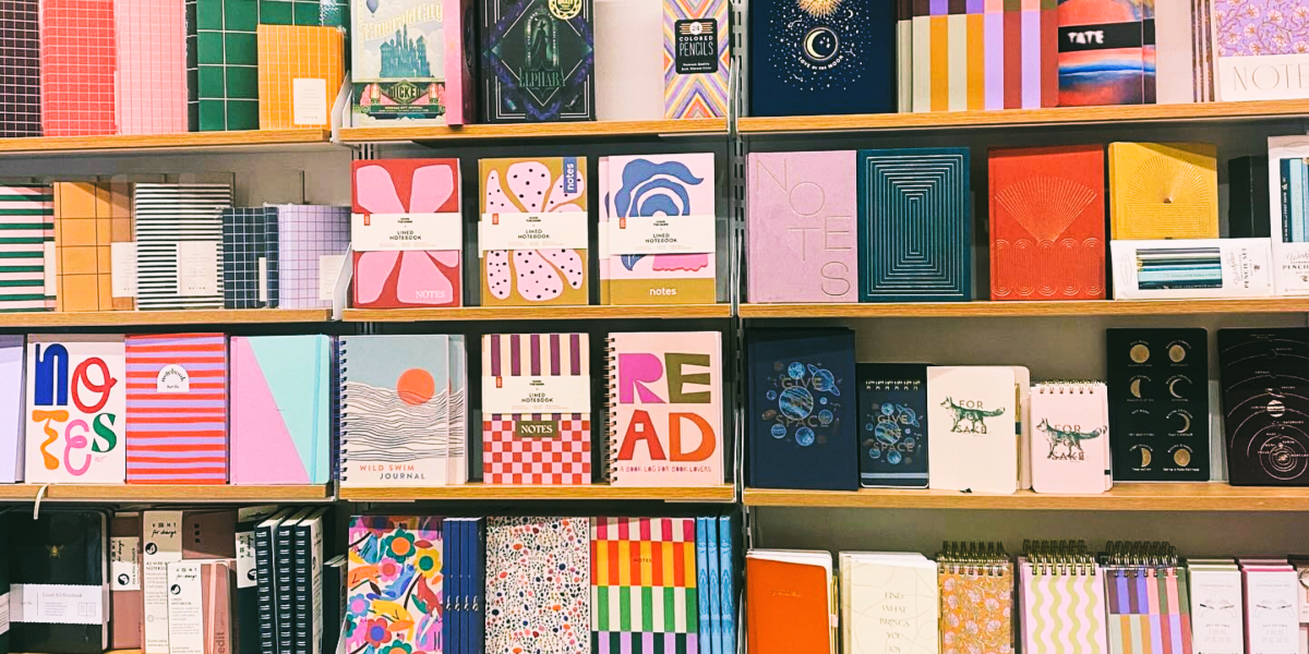 Waterstones shelves stocked with a range of colourful notebooks with abstract designs, illustrations and inspirational text.