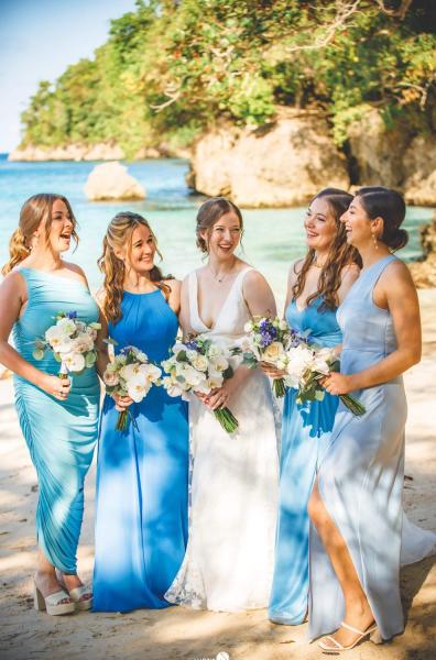 A bride stands with her bridesmaids dressed in blue on the beach in Jamaica