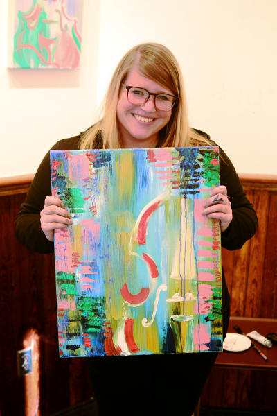 Artist Camille Hayes poses holding one of her paintings from her exhibition, "B Sides," at tiny ATH gallery in Athens, GA.