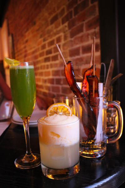 Green drink in champagne flute with lemon, vodka cocktail with cream and lemon and empty glass with bacon