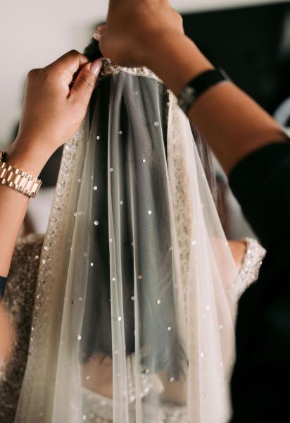 Hands of a hairstylist adjusting a veil on a bride's head