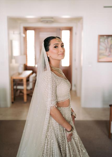 A bride in traditional Indian wedding attire looks over her shoulder at the camera at her wedding in Jamaica