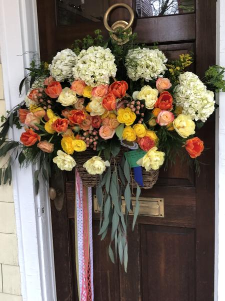 A May Day basket with ribbons hanging down and beautiful hydrangeas, roses and ranunculus