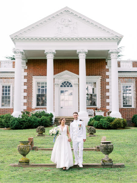 Navy groom and bride in front of Whitehall Manor.