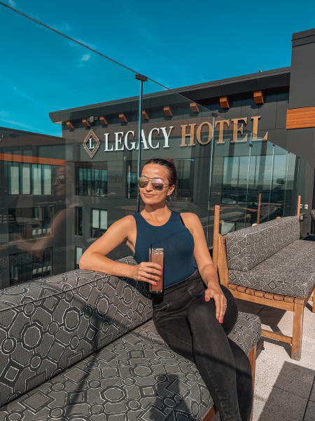 Woman enjoying a cocktail on the Legacy Hotel rooftop in Green Bay, Wisconsin at Cardinal's Crest Rooftop Gastro Pub.