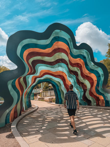 Man walking under colorful wavy sculpture at the Green Bay Botanical Garden in Green Bay, Wisconsin.
