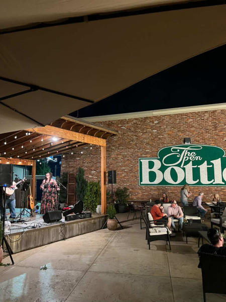A picture at The Open Bottle in Madison where people are outside on a patio listening to a band play while they enjoy their meals