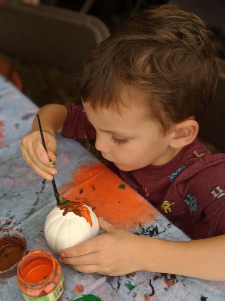 Child painting small pumpkin