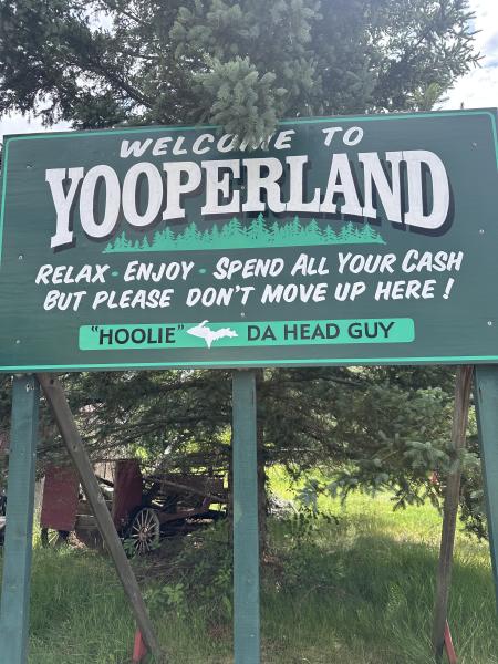 A sign outside of Da Yooper's Tourist Trap that says "Welcome to Yooperland—Relax. Enjoy. Spend all your cash. But please don't move up here!"