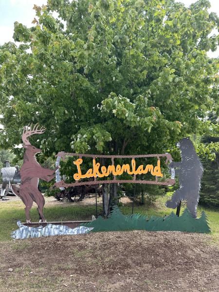 The metal sculpture of a deer and bear holding the entrance sign to Lakenenland