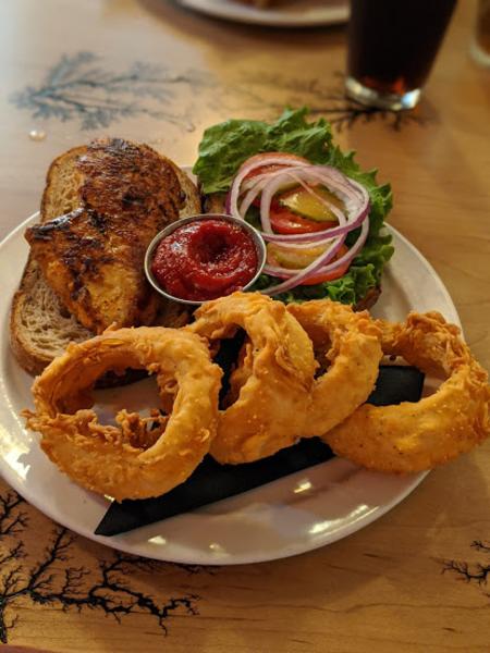 elusive cow in bellevue ky grilled chicken sandwich served open faced with a side of onion rings
