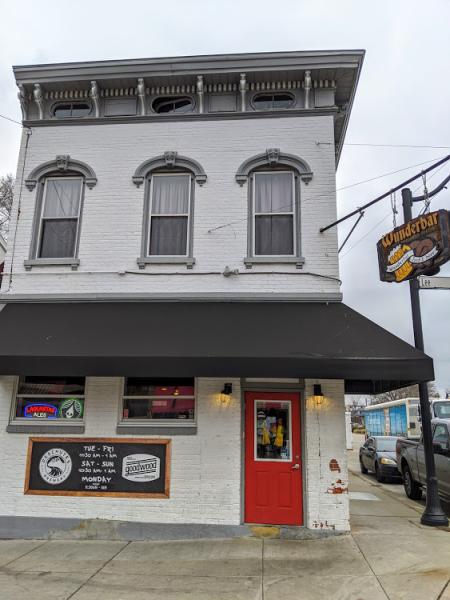 exterior shot of a white building with black awning and red door with sign showing wunderbar in covington kentucky