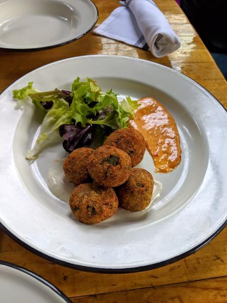 goetta hush puppies from libbys southern comfort in covington ky with green garnish and sauce on the side of a white plate