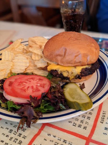 photo of a cheeseburger, garden on the side, with a side of potato chips