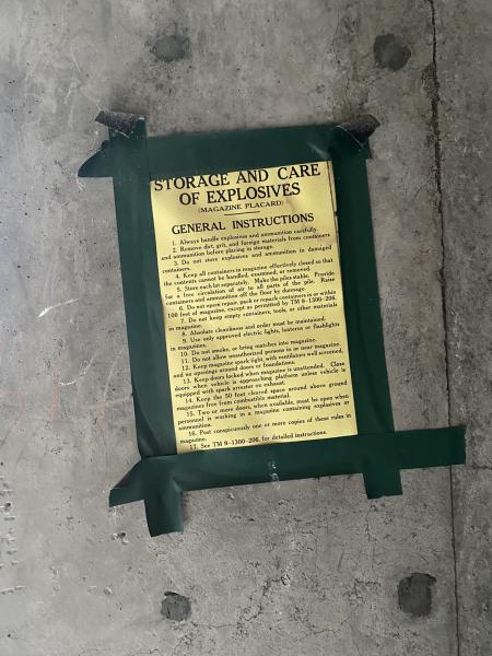 yellow list of rules about explosives taped to concrete wall with green tape